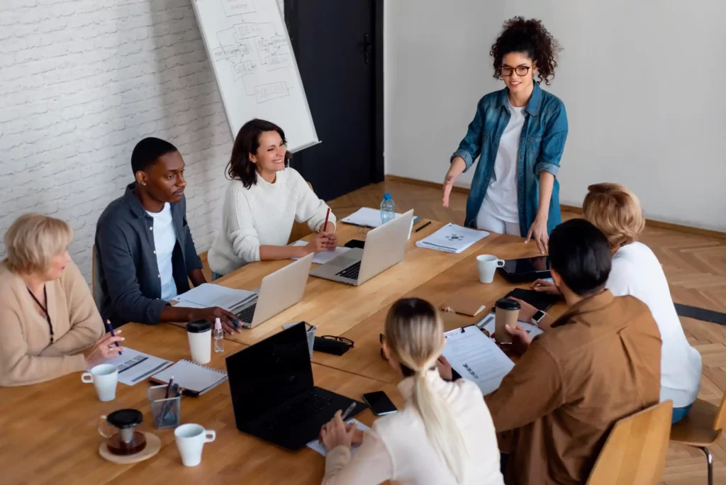 Vue plongeante sur un groupe d’apprenants en formation commerce et management à Ecoris, travaillant ensemble autour d’une table lors d’une réunion professionnelle.