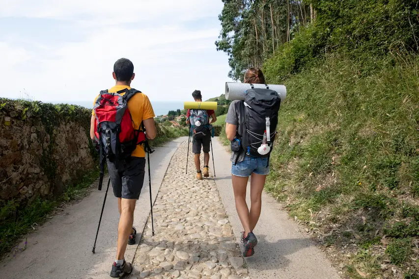 Trois backpackers marchant sur le chemin de Saint-Jacques-de-Compostelle, en pleine découverte.