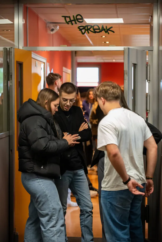 "Étudiants en discussion devant l’espace détente 'The Break' dans un campus, ambiance conviviale et dynamique.