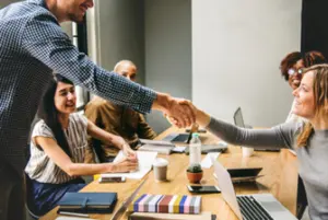 Réunion d’équipe en entreprise avec une poignée de main entre deux collègues, symbolisant la collaboration et le travail en équipe.